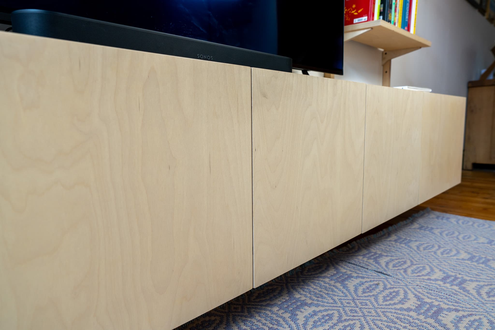 Custom-size wooden modular shelving units fitted below a wall-mounted TV