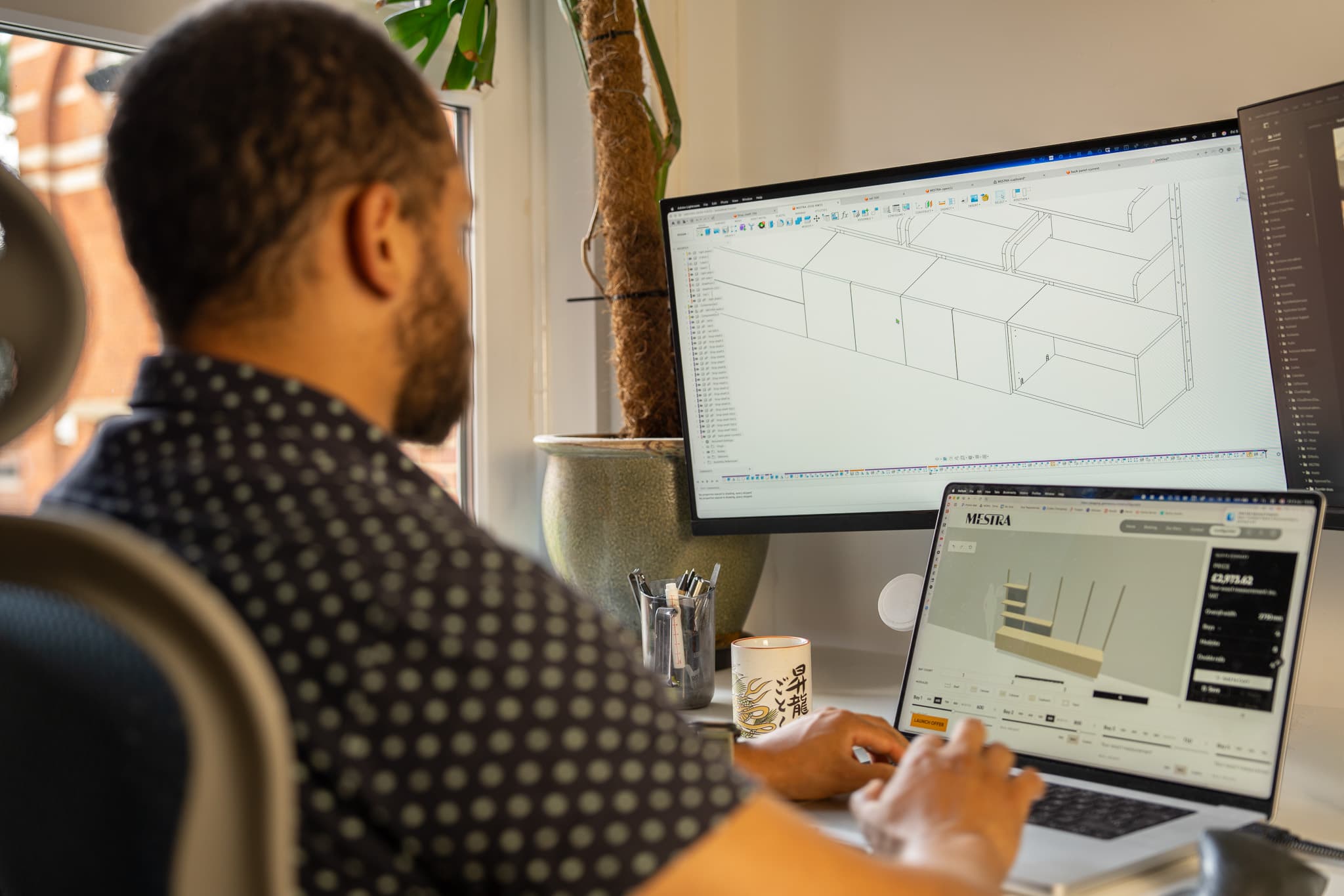 Designer planning custom modular shelving units in CAD on a laptop and monitor
